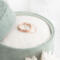 A close-up of a soft green velvet box, revealing a set of rose gold diamond-textured stacking rings resting on a white fabric.

